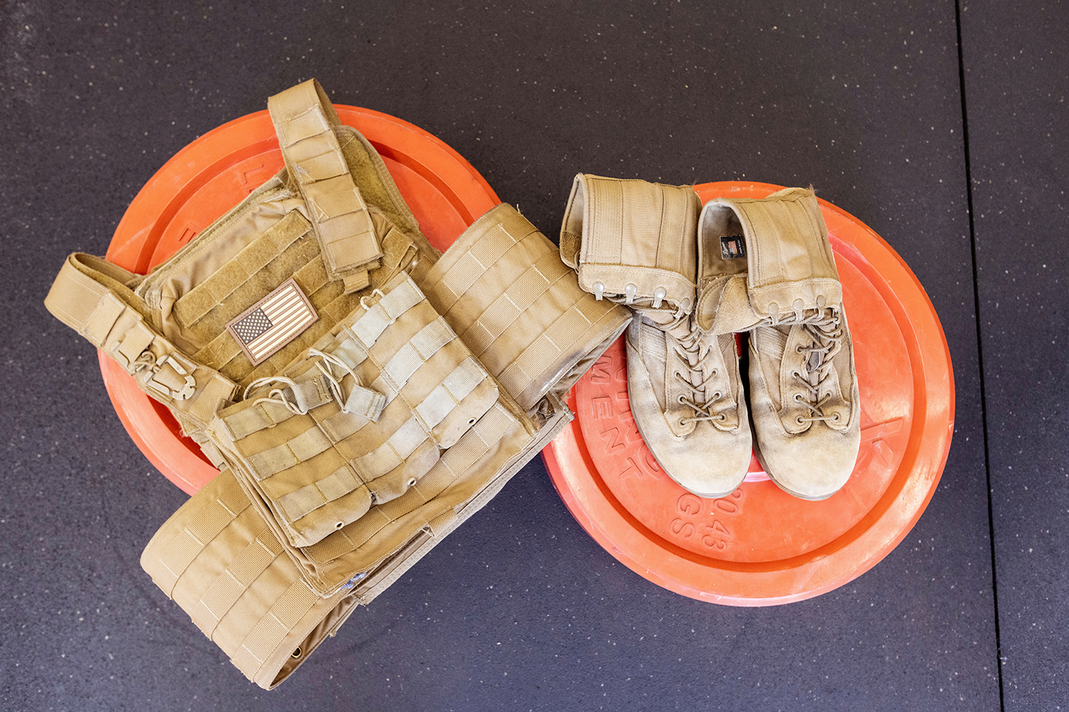 Military boots and tactical vest on red weight plates